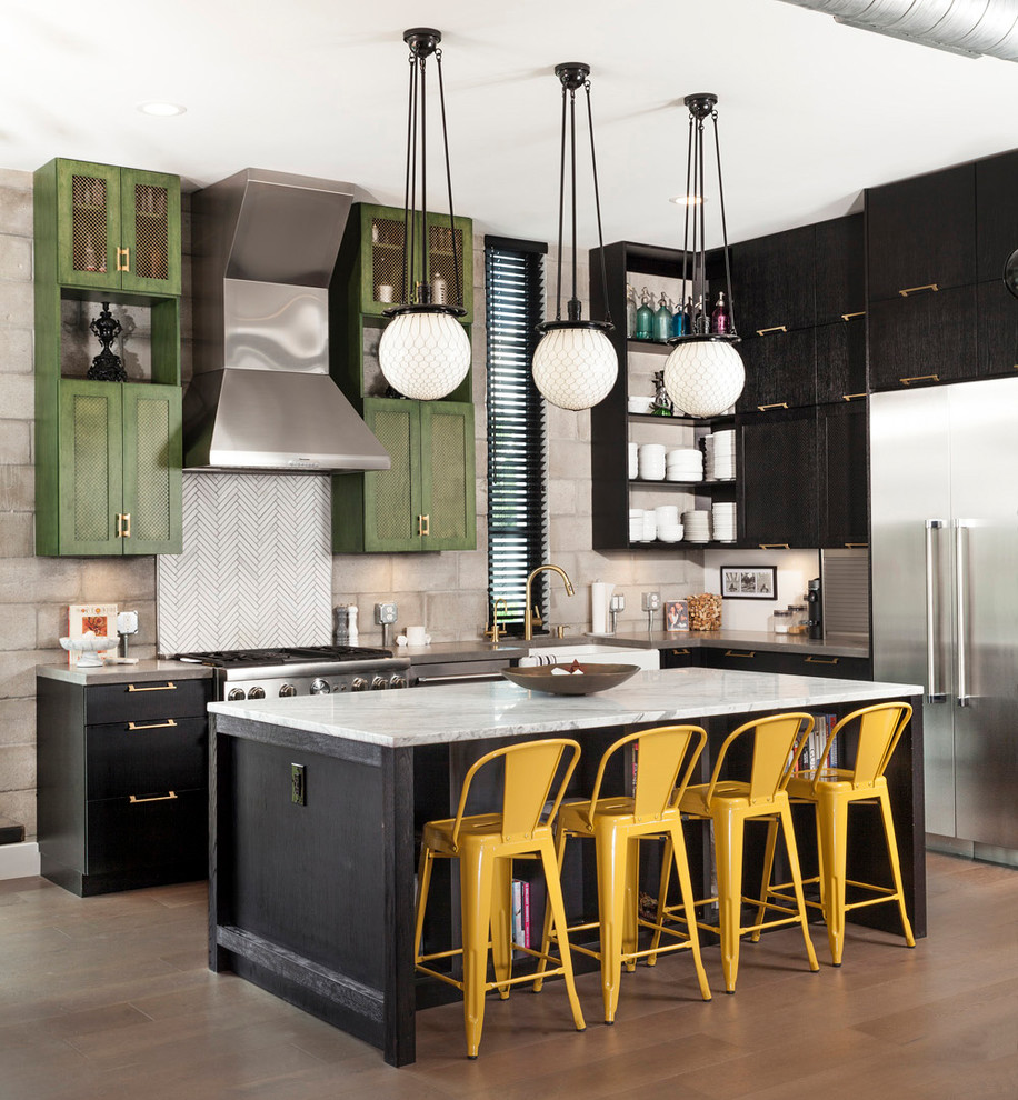 This is an example of an industrial l-shaped kitchen in Tampa with a farmhouse sink, green cabinets, white splashback, stainless steel appliances, medium hardwood floors, with island and grey benchtop.
