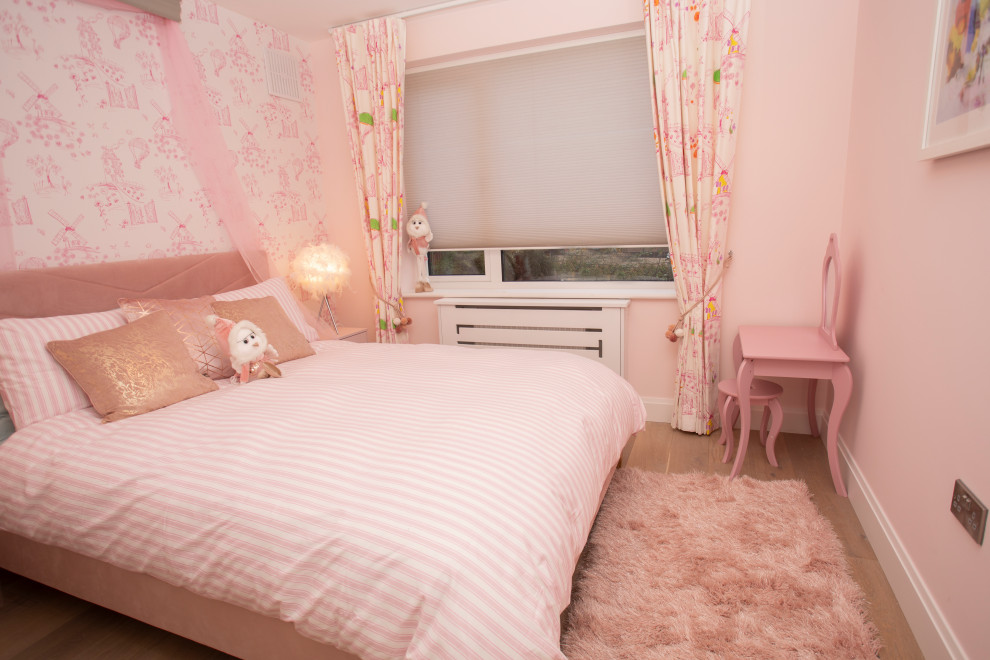 This is an example of a modern bedroom in Dublin with pink walls and laminate floors.