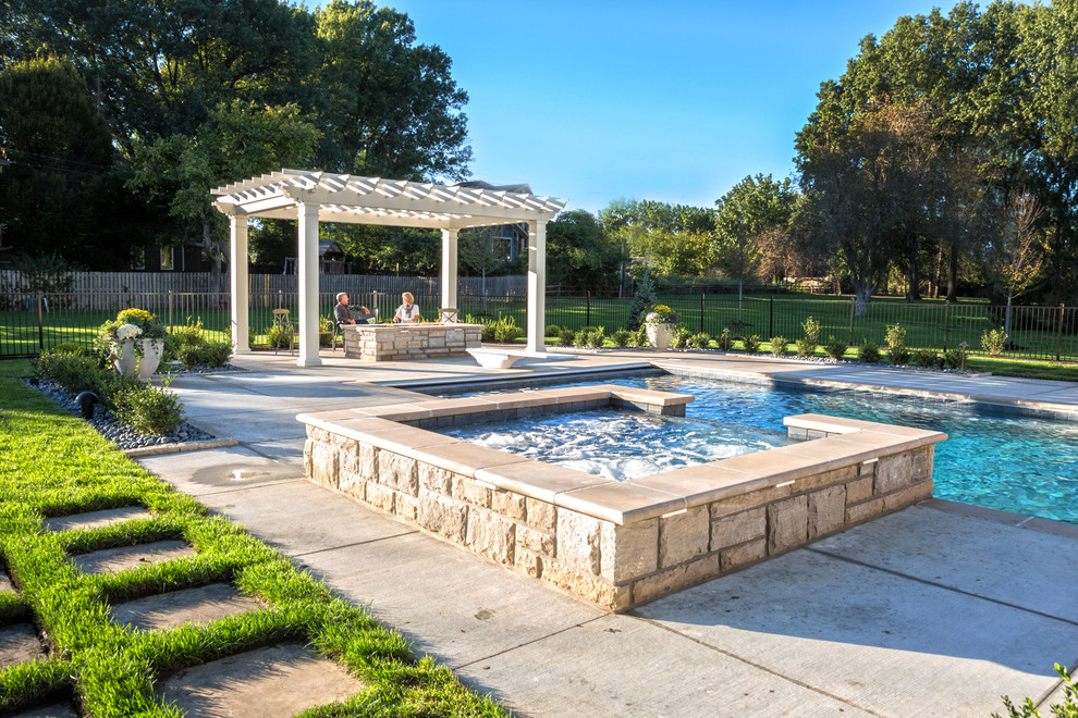 Photo of a large traditional backyard rectangular natural pool in Kansas City with a hot tub and natural stone pavers.