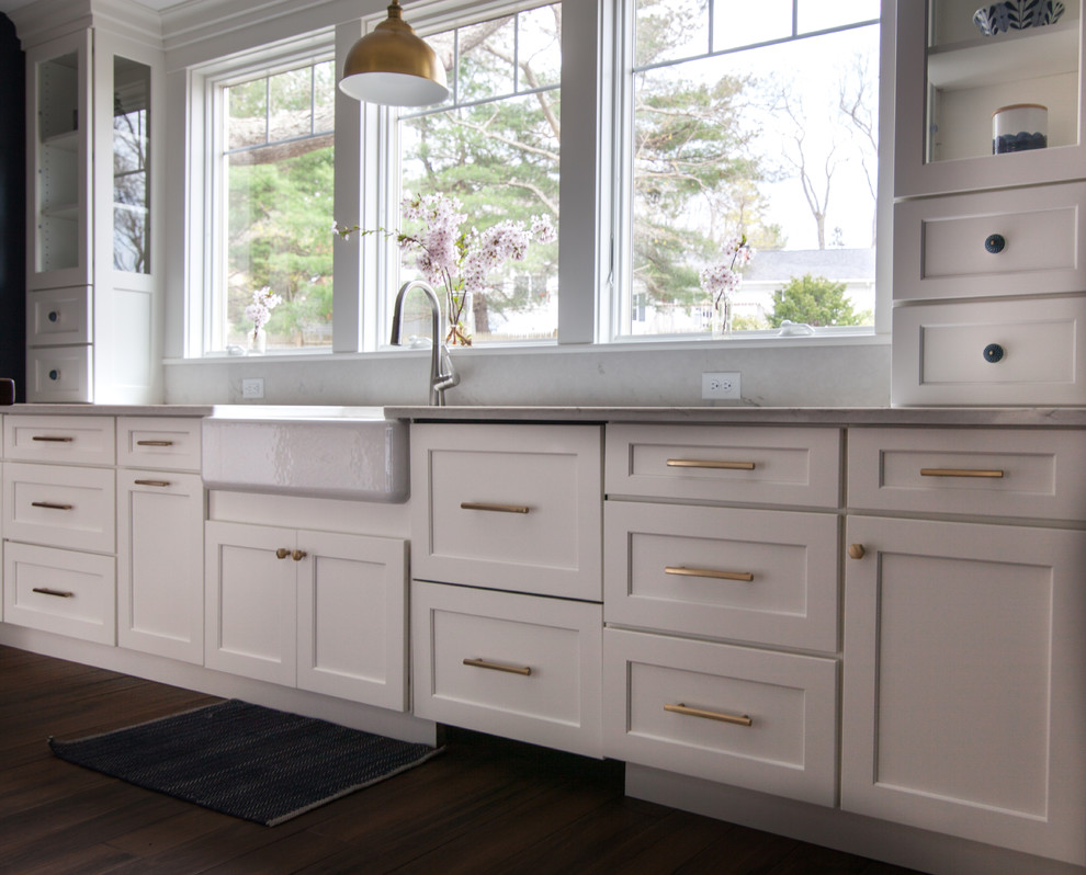Inspiration for a large transitional l-shaped enclosed kitchen remodel in Boston with a farmhouse sink, shaker cabinets, white cabinets, quartz countertops, white backsplash, stainless steel appliances, an island and white countertops