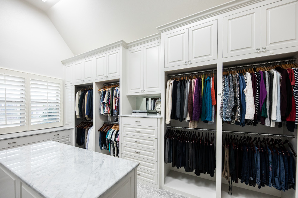 Inspiration for a large traditional gender neutral walk-in wardrobe in Dallas with beaded cabinets, white cabinets, carpet, grey floors and a vaulted ceiling.