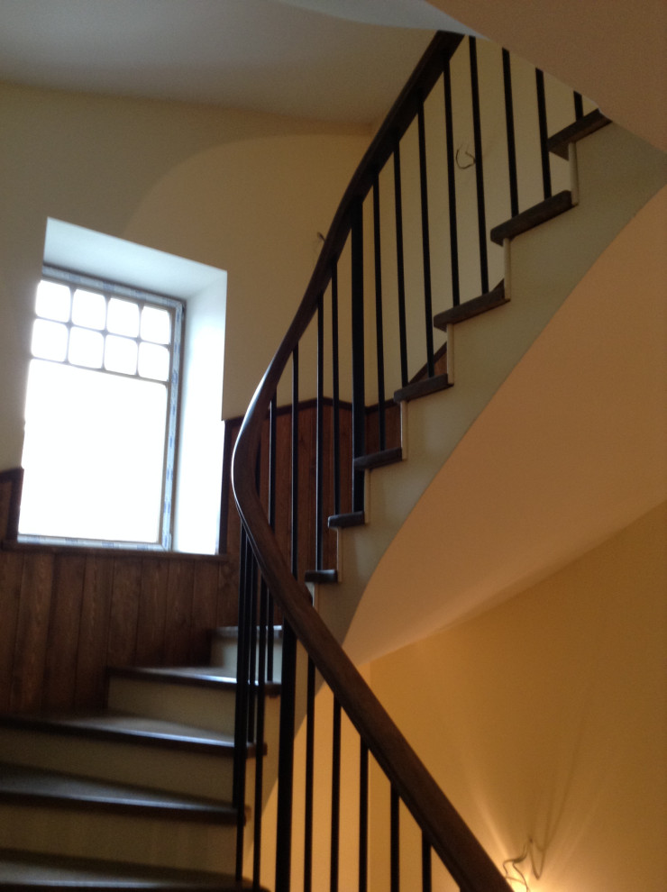 Mid-sized traditional wood curved staircase in Moscow with wood risers, metal railing and wallpaper.