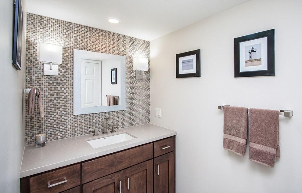 Mid-sized transitional beige tile, brown tile, gray tile and mosaic tile powder room photo in Phoenix with shaker cabinets, medium tone wood cabinets, gray walls, an undermount sink and solid surface countertops