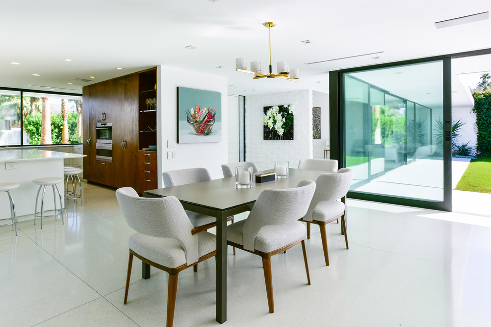 This is an example of a midcentury kitchen/dining combo in Los Angeles with white walls and beige floor.