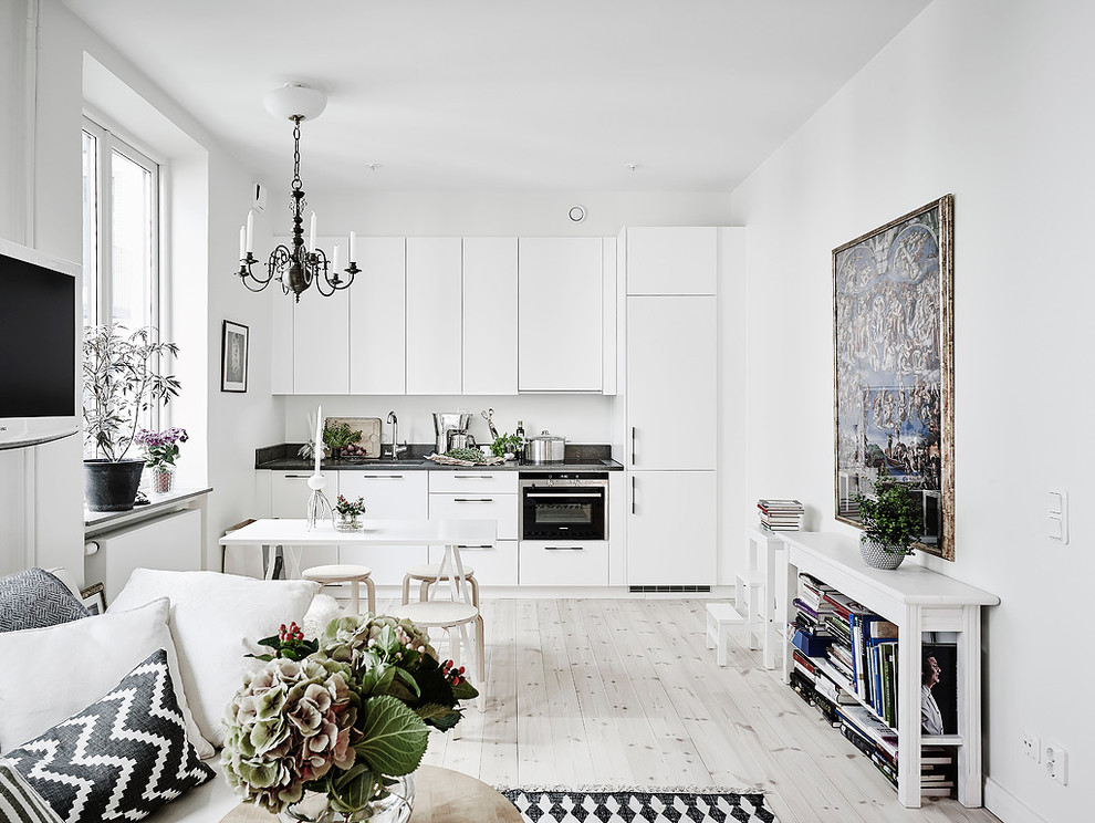 Small scandinavian single-wall eat-in kitchen in Gothenburg with flat-panel cabinets, white cabinets, granite benchtops, light hardwood floors, no island and stainless steel appliances.