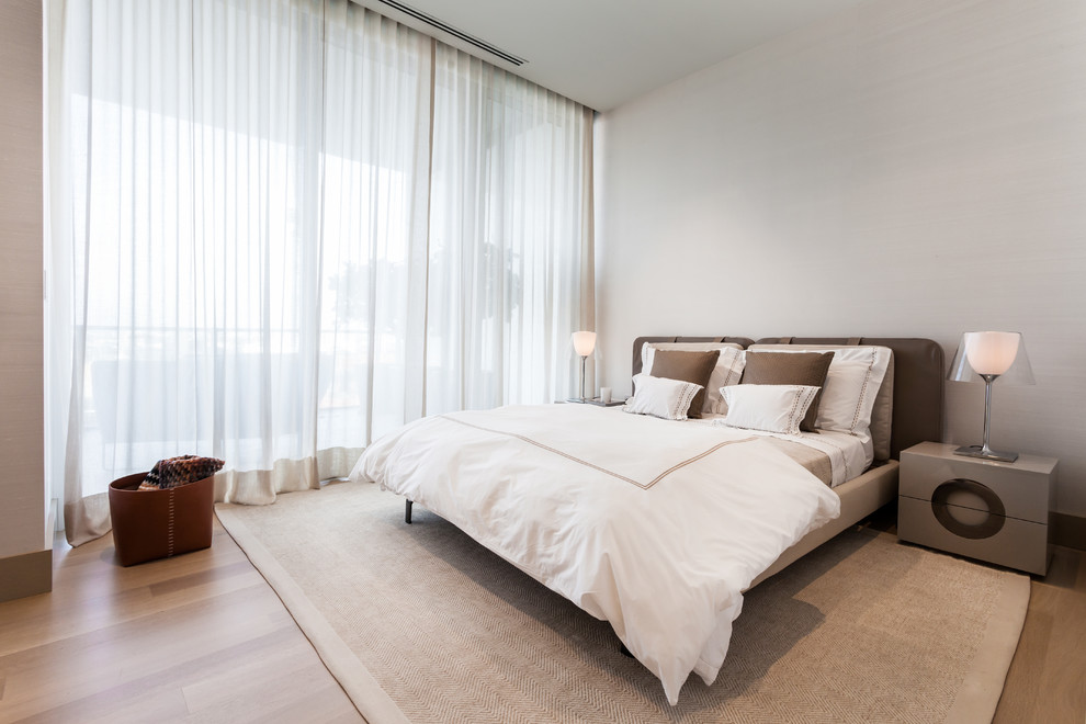 Design ideas for a contemporary bedroom in Miami with white walls and medium hardwood floors.