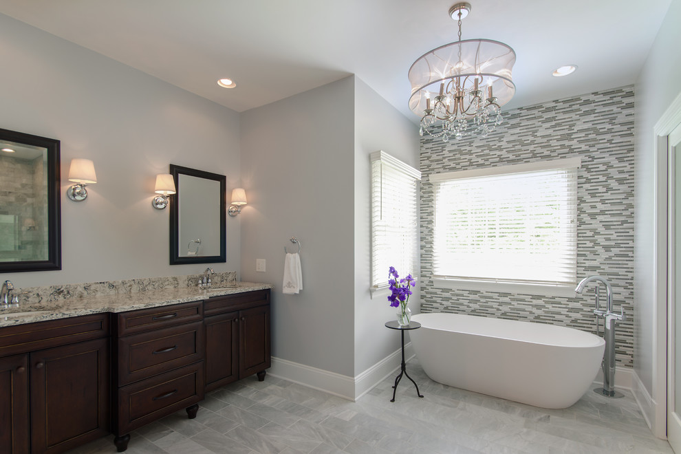 This is an example of a large transitional master bathroom in Richmond with recessed-panel cabinets, dark wood cabinets, a freestanding tub, gray tile, white tile, matchstick tile, grey walls, porcelain floors and granite benchtops.