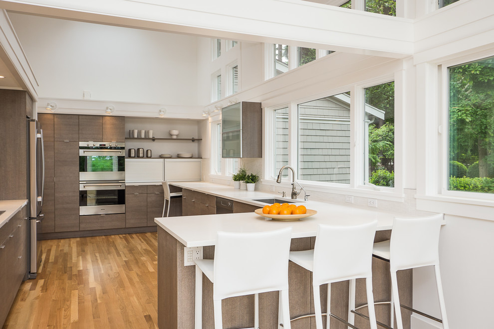 Design ideas for a contemporary u-shaped kitchen in Seattle with a drop-in sink, flat-panel cabinets, dark wood cabinets and stainless steel appliances.