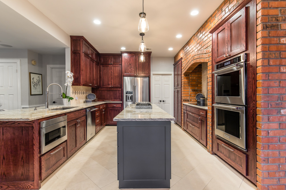 Inspiration for a large traditional u-shaped eat-in kitchen in Dallas with an undermount sink, shaker cabinets, dark wood cabinets, granite benchtops, beige splashback, travertine splashback, stainless steel appliances, limestone floors, with island, beige floor and beige benchtop.