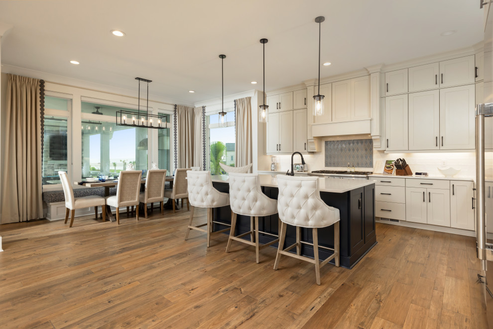 Example of a large transitional kitchen design with a farmhouse sink, beige cabinets, white backsplash, ceramic backsplash, stainless steel appliances and an island