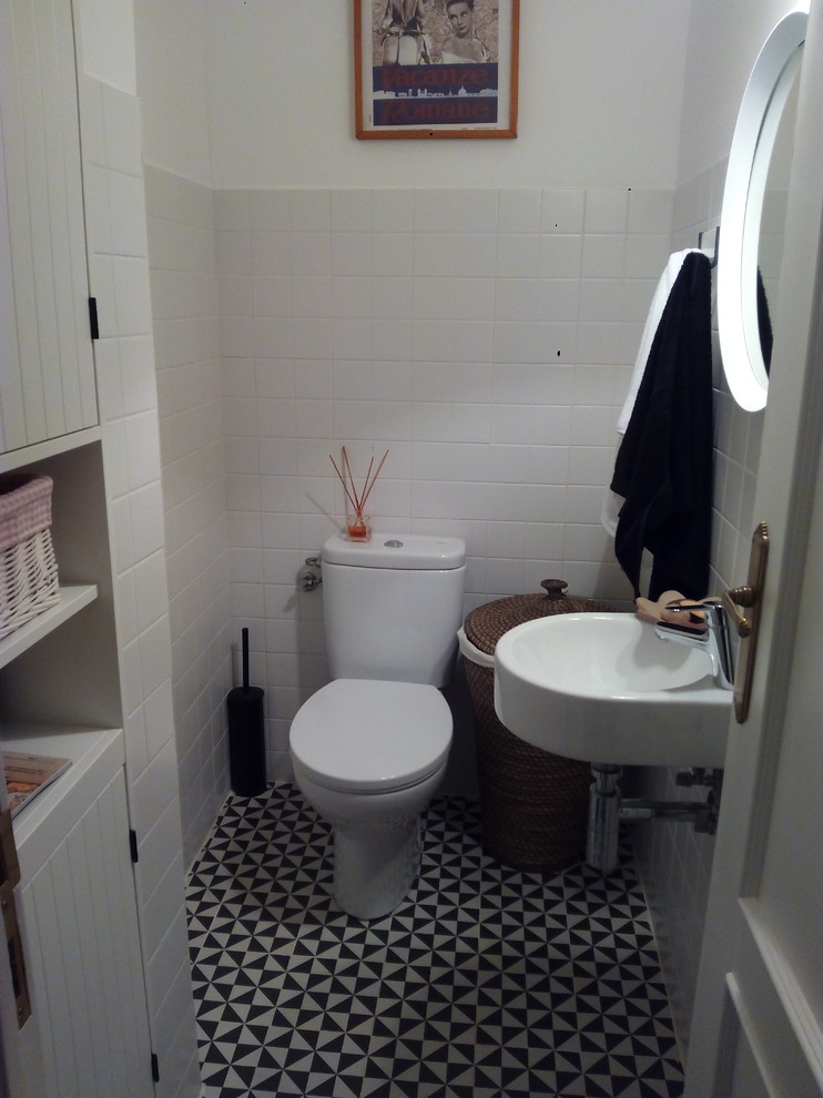 Photo of a small transitional powder room in Madrid with a two-piece toilet and a wall-mount sink.