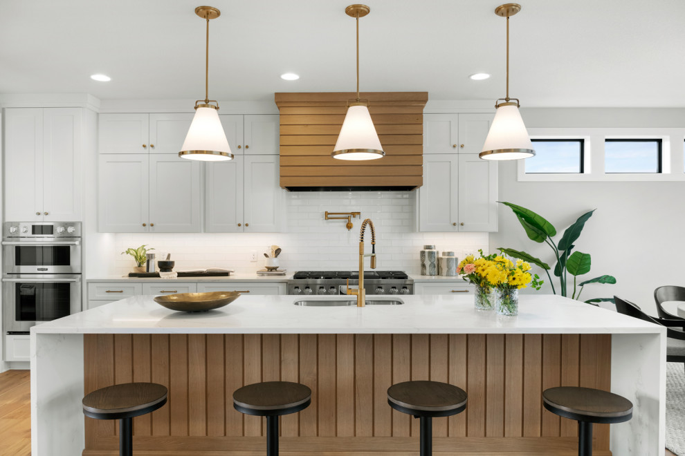 Inspiration for a transitional eat-in kitchen in Minneapolis with white cabinets, quartzite benchtops, white splashback, stainless steel appliances, light hardwood floors, with island and white benchtop.