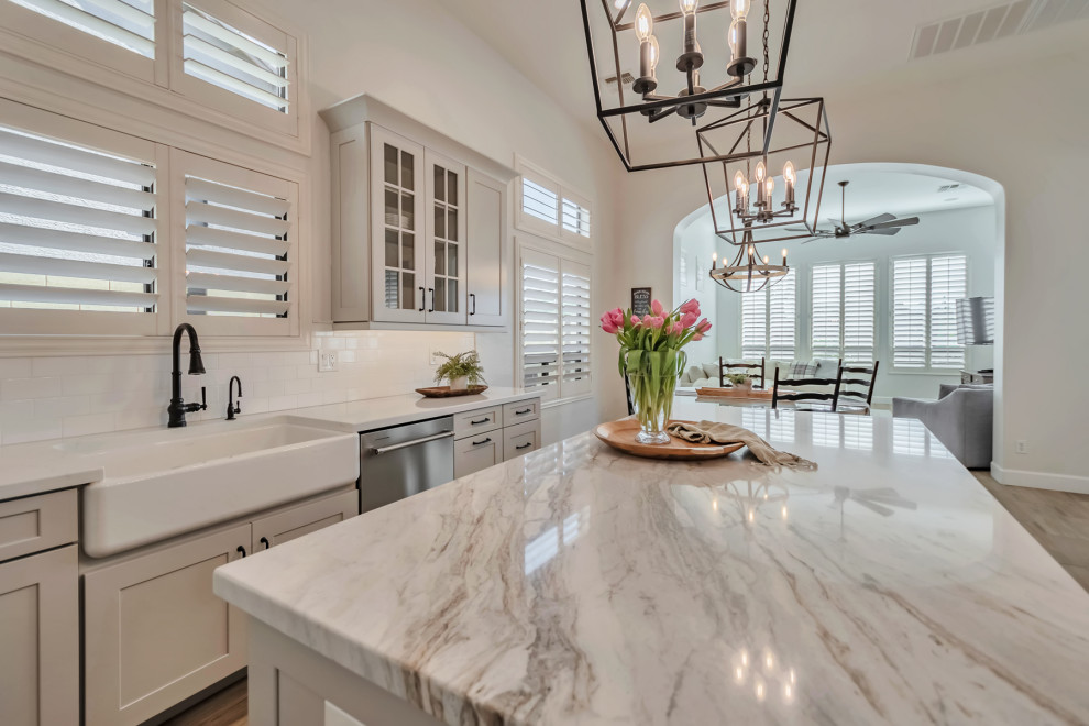 Kitchen - large transitional u-shaped porcelain tile, brown floor and exposed beam kitchen idea in Phoenix with a farmhouse sink, shaker cabinets, gray cabinets, quartzite countertops, white backsplash, porcelain backsplash, stainless steel appliances, an island and white countertops