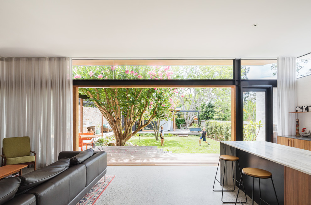 Inspiration for a mid-sized contemporary open concept living room in Sydney with white walls, concrete floors, a wood stove, a brick fireplace surround, a wall-mounted tv and grey floor.