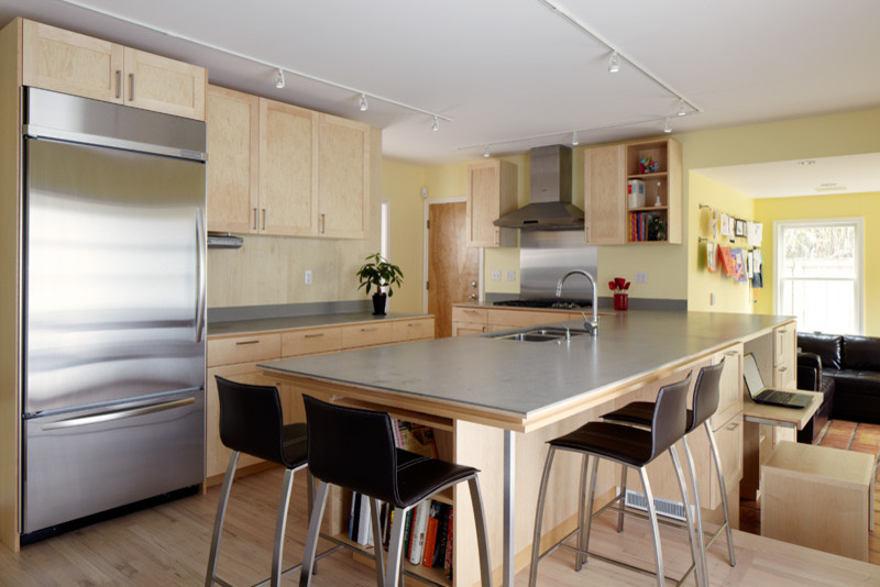 Mid-sized transitional l-shaped light wood floor eat-in kitchen photo in Seattle with an undermount sink, recessed-panel cabinets, light wood cabinets, solid surface countertops, gray backsplash, stainless steel appliances and a peninsula
