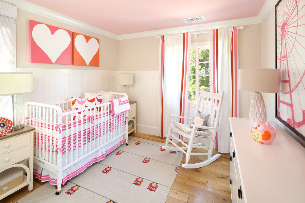 Design ideas for a traditional nursery for girls in San Francisco with beige walls and light hardwood floors.