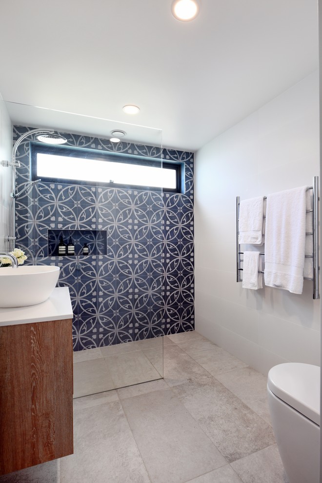 Inspiration for a mid-sized contemporary 3/4 bathroom in Sydney with white benchtops, medium wood cabinets, a curbless shower, blue tile, white walls, a vessel sink, beige floor and an open shower.
