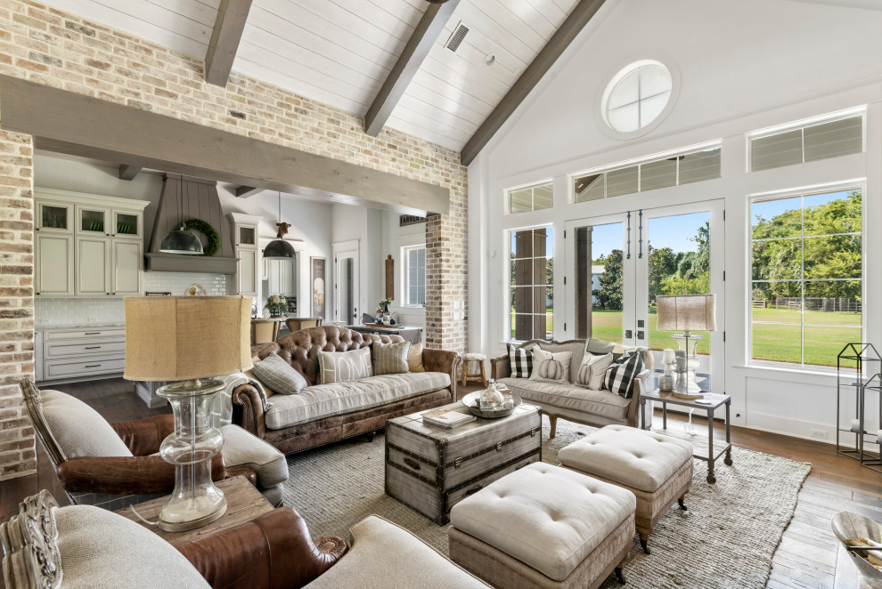 Country open concept living room in Houston with white walls, dark hardwood floors, brown floor, exposed beam, timber, vaulted and brick walls.