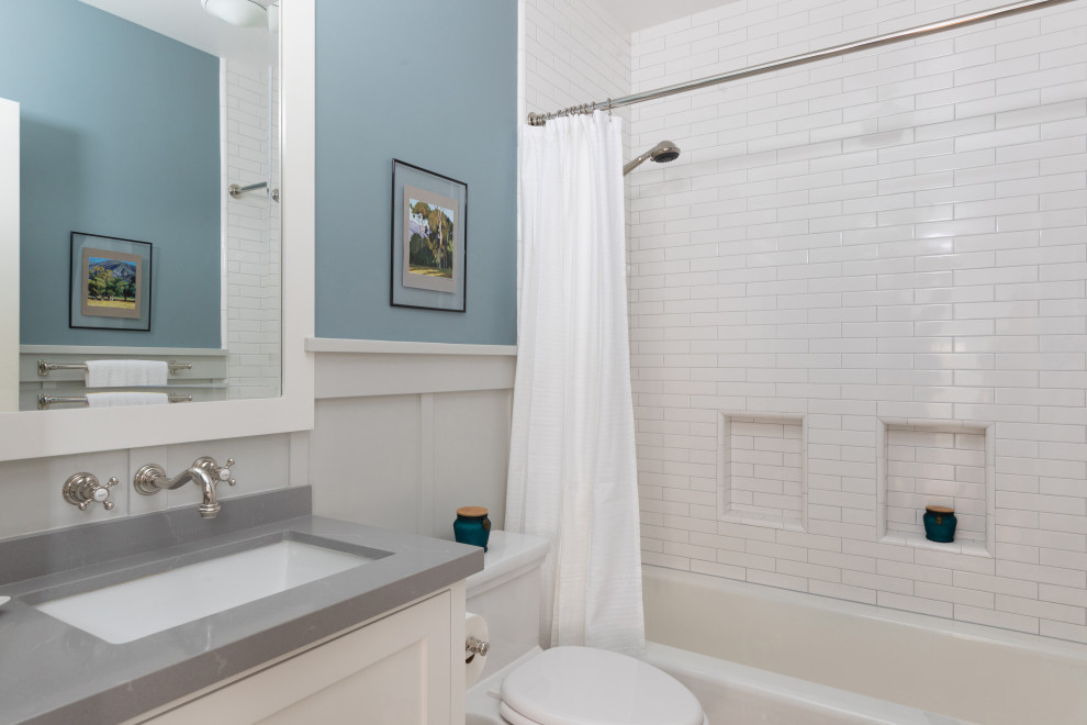 Amerikansk inredning av ett mellanstort grå grått en-suite badrum, med skåp i shakerstil, vita skåp, ett badkar i en alkov, en dusch/badkar-kombination, en toalettstol med hel cisternkåpa, keramikplattor, ett undermonterad handfat, bänkskiva i kvarts, vitt golv, vit kakel och blå väggar