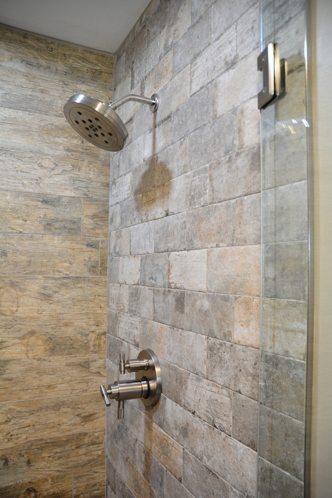 Example of a mid-sized mountain style master brown tile and ceramic tile ceramic tile and brown floor alcove shower design with raised-panel cabinets, light wood cabinets, a two-piece toilet, beige walls, an integrated sink, marble countertops, a hinged shower door and gray countertops