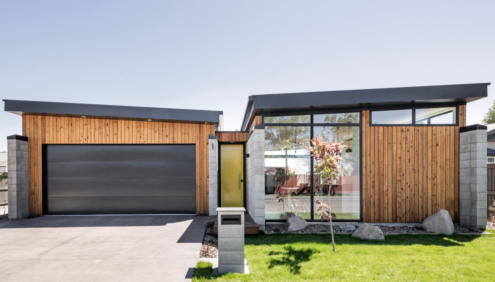 На фото: одноэтажный, разноцветный частный загородный дом среднего размера в современном стиле с комбинированной облицовкой и черной крышей с