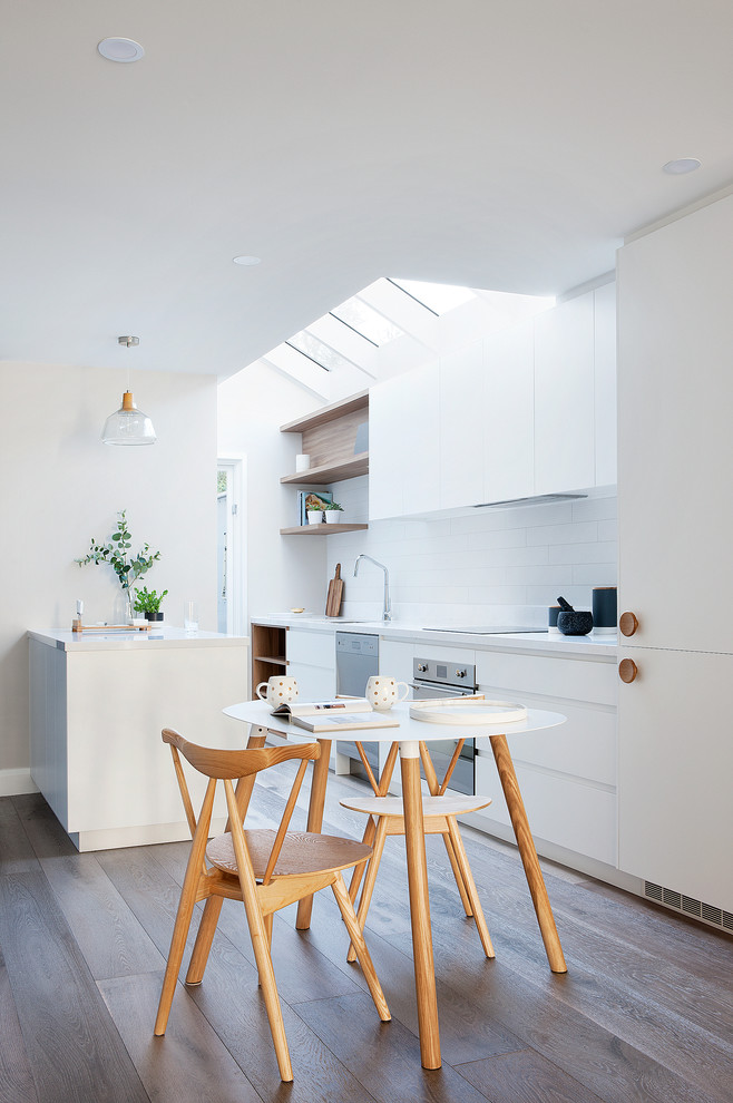 Inspiration for a large contemporary galley eat-in kitchen in Melbourne with white cabinets, white splashback, stainless steel appliances, light hardwood floors, a drop-in sink, beaded inset cabinets, subway tile splashback and with island.