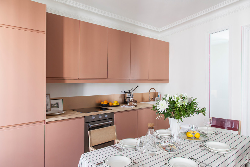 Contemporary single-wall eat-in kitchen in Paris with a drop-in sink, flat-panel cabinets, orange cabinets, wood benchtops, stainless steel appliances, no island and beige benchtop.