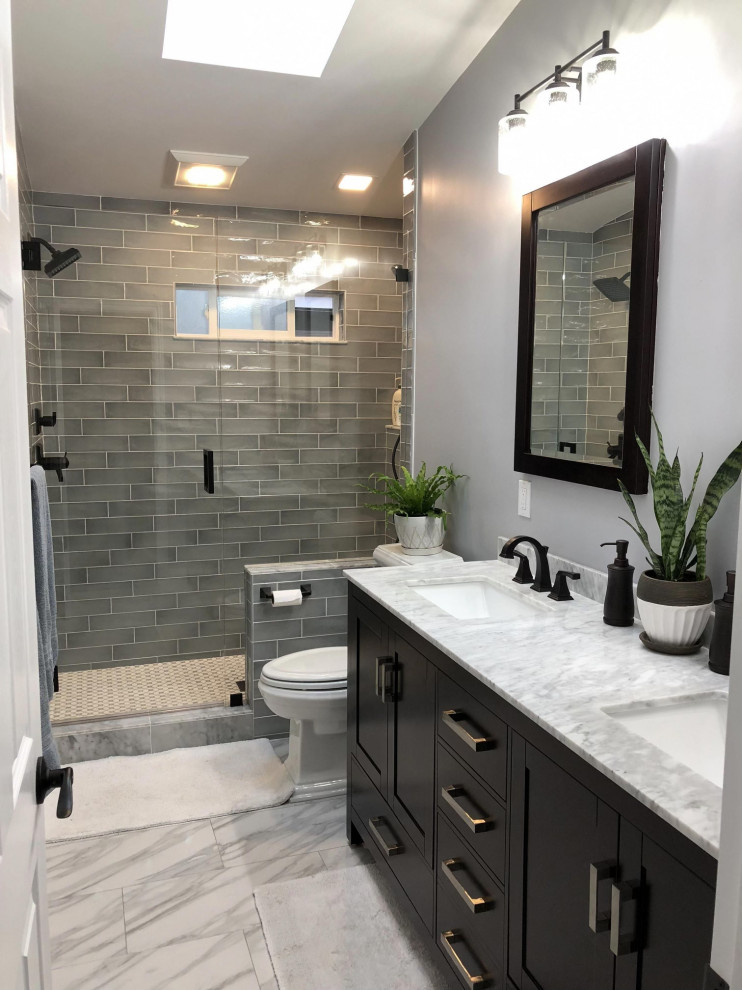 This is an example of a mid-sized midcentury 3/4 bathroom in New York with shaker cabinets, black cabinets, a two-piece toilet, green tile, subway tile, grey walls, porcelain floors, an undermount sink, marble benchtops, white floor, a hinged shower door, white benchtops, a double vanity and a freestanding vanity.