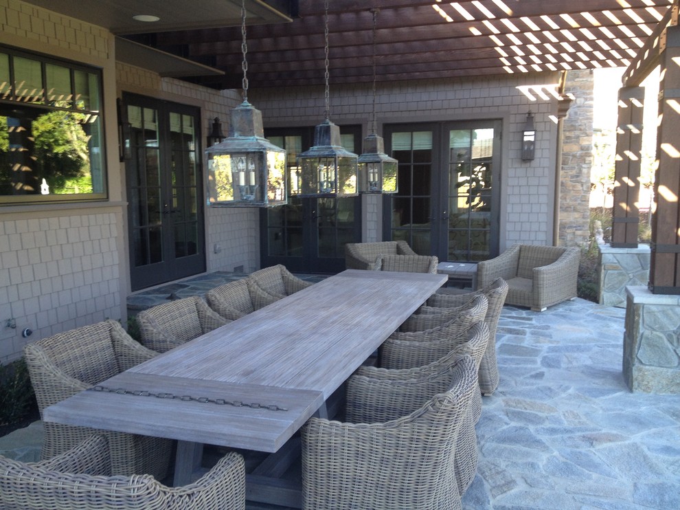 This is an example of a large country backyard patio in San Francisco with natural stone pavers and a pergola.