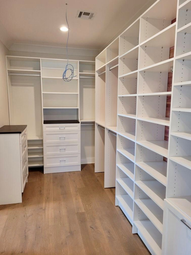 Inspiration for a medium sized classic gender neutral walk-in wardrobe in New York with recessed-panel cabinets, white cabinets, medium hardwood flooring and white floors.