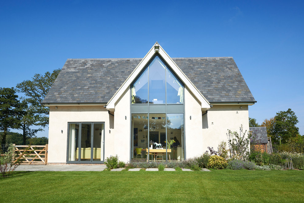 This is an example of a large country two-storey stucco white house exterior in Wiltshire with a gable roof and a shingle roof.
