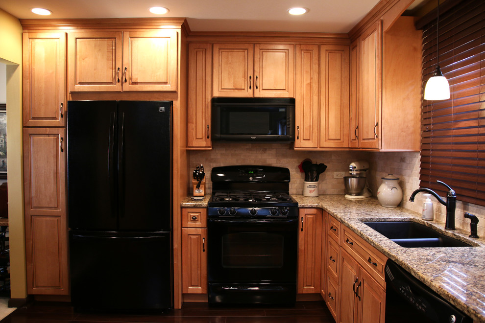 Open concept kitchen - small transitional u-shaped laminate floor open concept kitchen idea in Chicago with an undermount sink, raised-panel cabinets, medium tone wood cabinets, granite countertops, beige backsplash, subway tile backsplash, black appliances, black walls and a peninsula