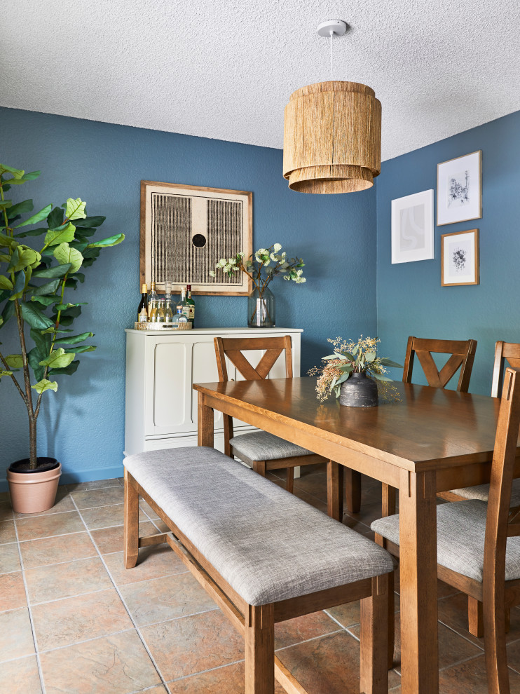 Réalisation d'une petite salle à manger tradition fermée avec un mur bleu, tomettes au sol, aucune cheminée et un sol marron.