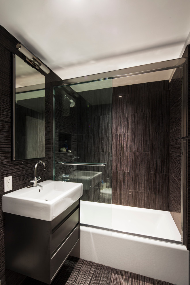This is an example of a mid-sized eclectic bathroom in New York with flat-panel cabinets, black cabinets, an alcove tub, an alcove shower, a one-piece toilet, black tile, ceramic tile, black walls, ceramic floors, a console sink, solid surface benchtops, black floor, an open shower and white benchtops.