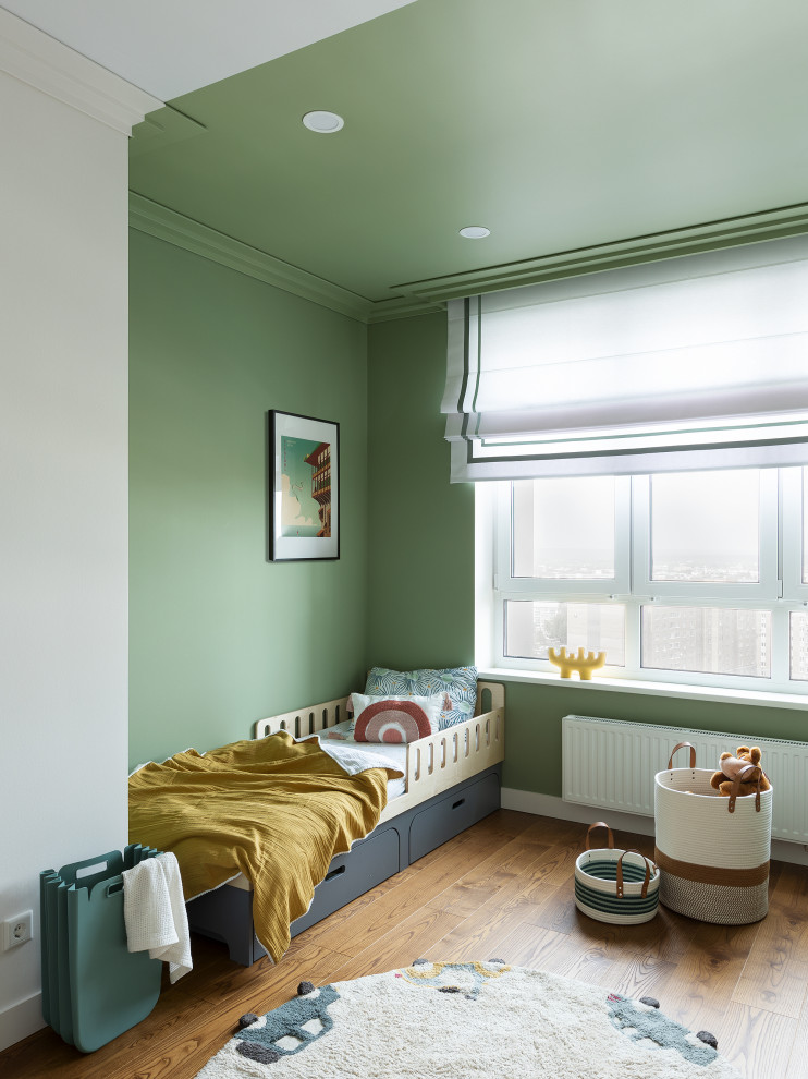 Idée de décoration pour une chambre d'enfant design avec un mur vert, un sol en bois brun et un sol marron.