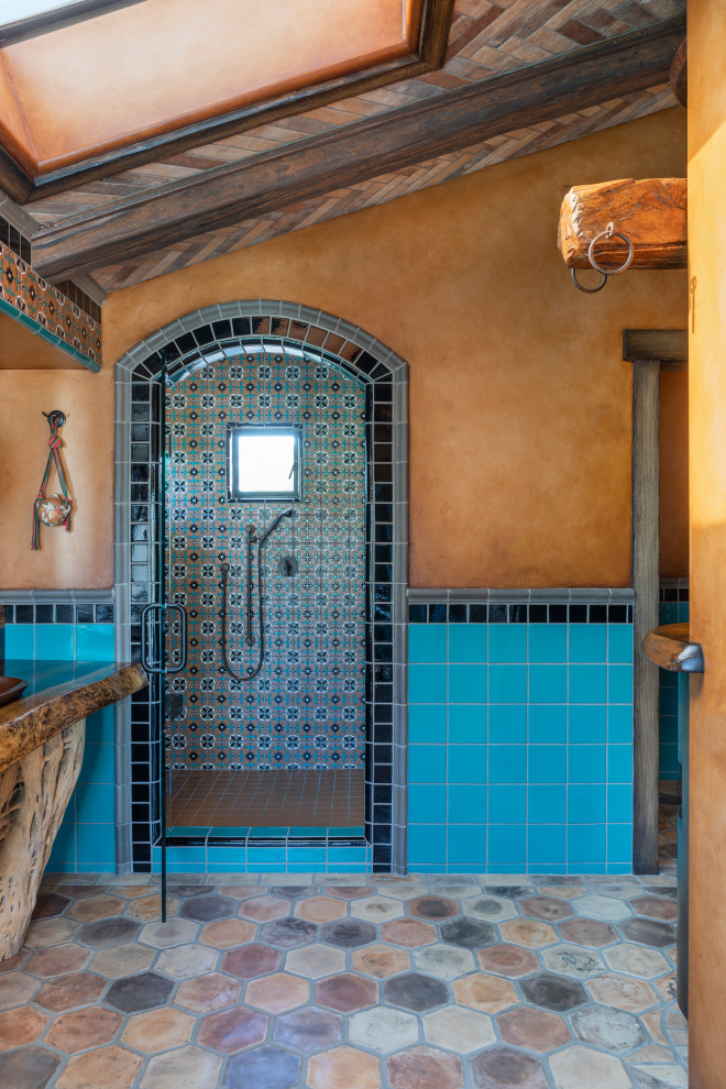 Photo of a bathroom in Los Angeles with an alcove shower, blue tile, orange walls, wood benchtops, brown floor, a hinged shower door, brown benchtops and vaulted.