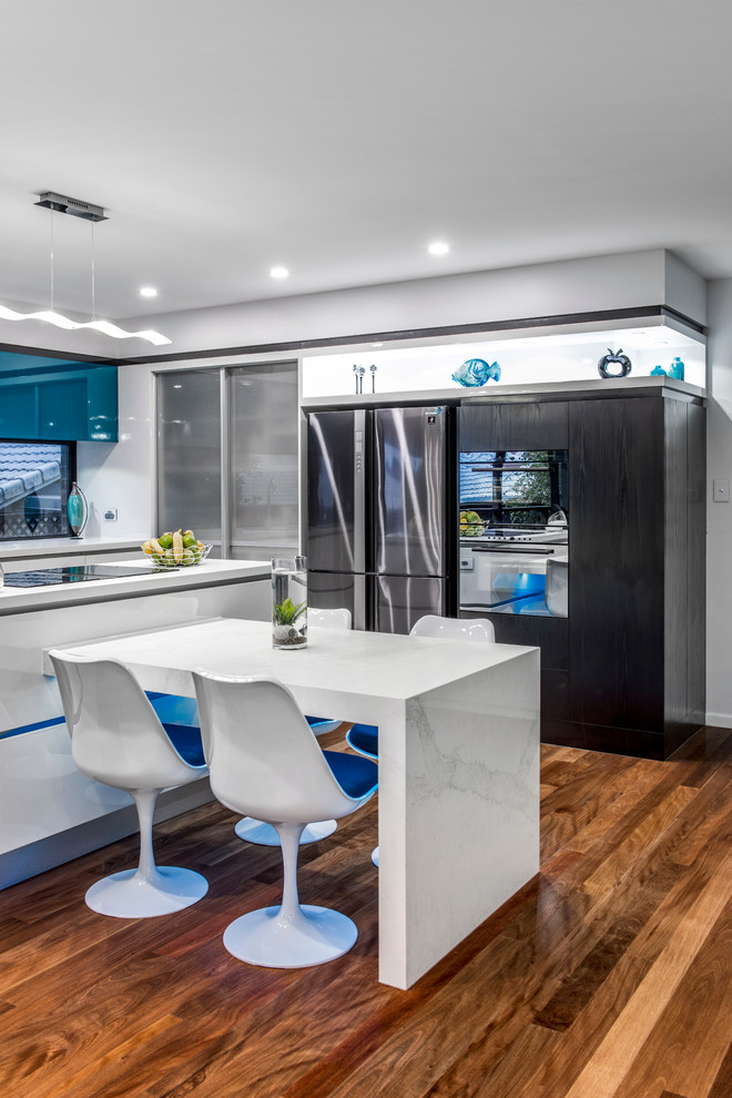 Mid-sized contemporary l-shaped kitchen pantry in Brisbane with an undermount sink, flat-panel cabinets, turquoise cabinets, quartz benchtops, black appliances, medium hardwood floors and with island.