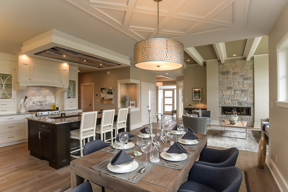 Photo of a transitional open plan dining in Vancouver with beige walls, medium hardwood floors and a stone fireplace surround.