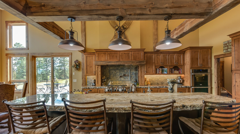 Large mountain style l-shaped medium tone wood floor open concept kitchen photo with recessed-panel cabinets, medium tone wood cabinets, stone tile backsplash, stainless steel appliances, an island, an undermount sink, granite countertops and beige backsplash