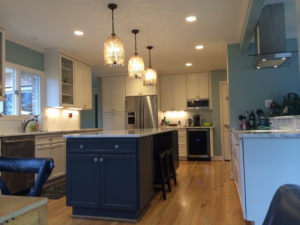 Inspiration for a mid-sized transitional u-shaped medium tone wood floor and brown floor eat-in kitchen remodel in DC Metro with an undermount sink, recessed-panel cabinets, white cabinets, marble countertops, white backsplash, subway tile backsplash, stainless steel appliances and an island