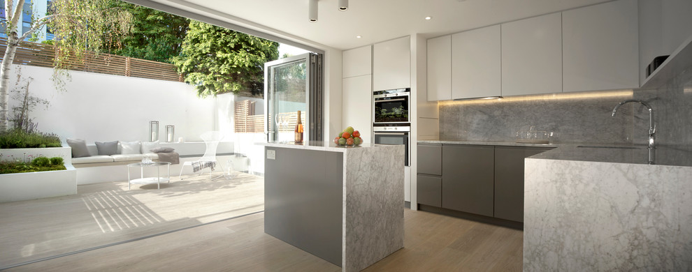 Design ideas for a mid-sized contemporary l-shaped eat-in kitchen in London with a drop-in sink, flat-panel cabinets, white cabinets, marble benchtops, grey splashback, stone slab splashback, stainless steel appliances, medium hardwood floors and with island.