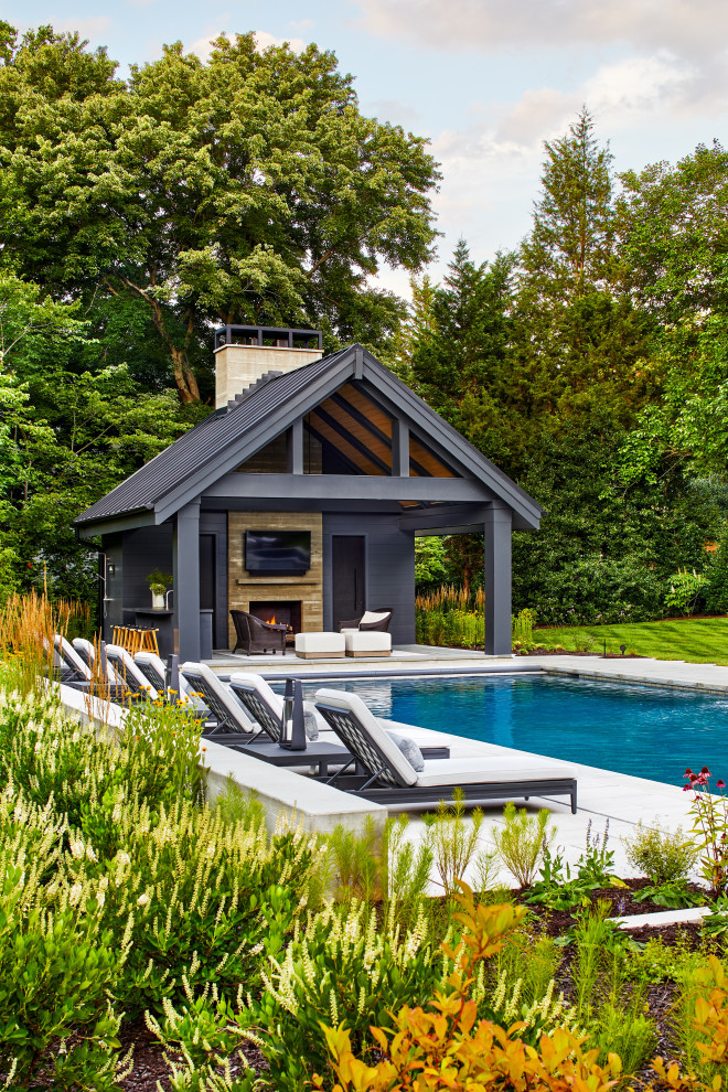 Пример оригинального дизайна: большой прямоугольный бассейн на заднем дворе с домиком у бассейна и мощением тротуарной плиткой