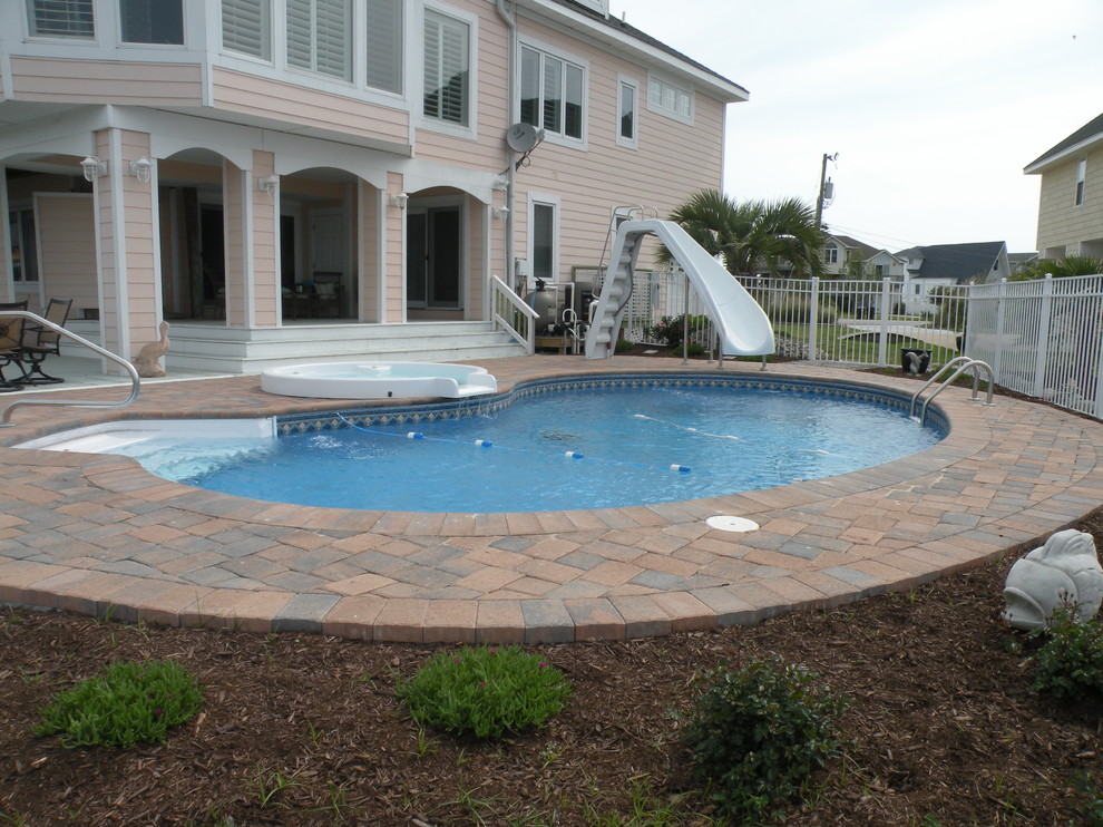 Inspiration for a mid-sized backyard brick and kidney-shaped hot tub remodel