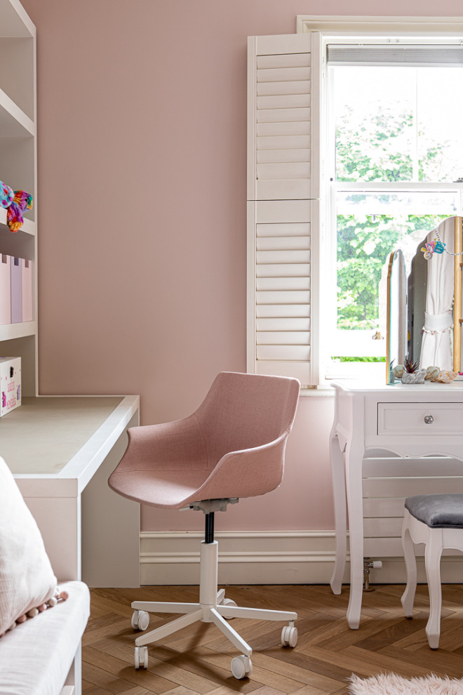 This is an example of a medium sized contemporary children’s room for girls in London with pink walls, light hardwood flooring, grey floors, wallpapered walls and feature lighting.