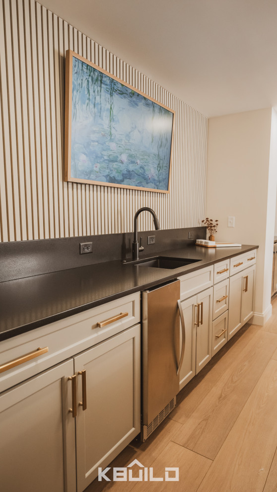 Example of a large home bar design in St Louis with beige cabinets, quartzite countertops and black countertops