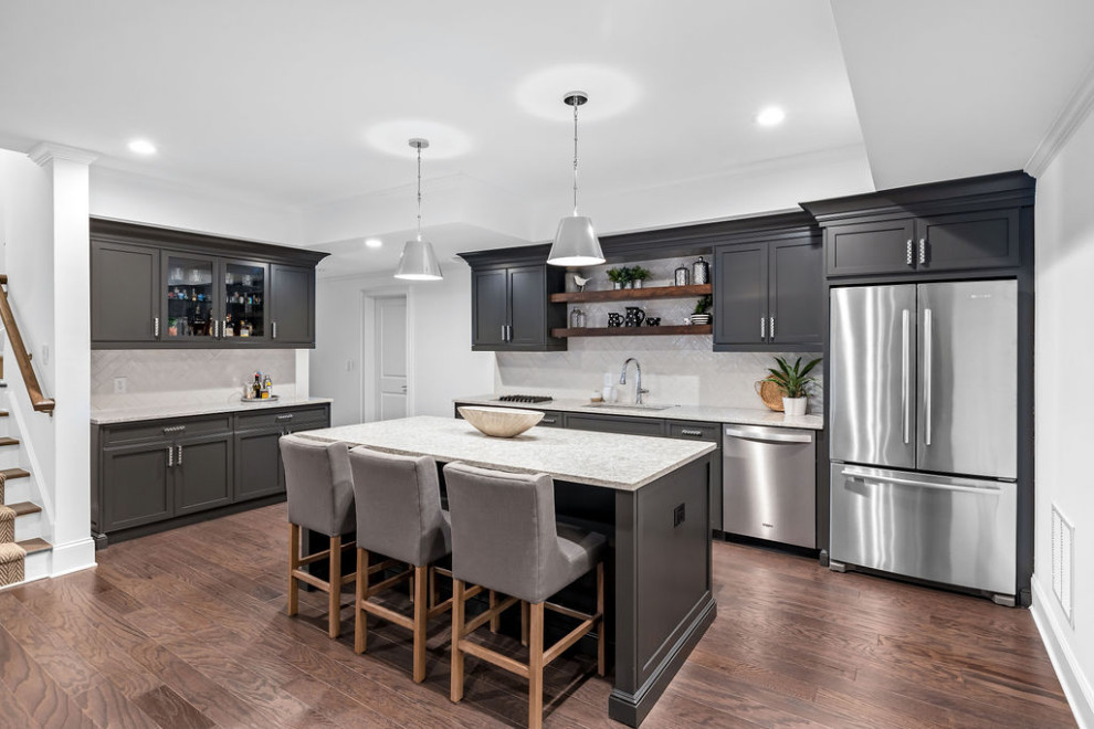 This is an example of a large traditional kitchen/diner in Atlanta with a submerged sink, shaker cabinets, black cabinets, quartz worktops, white splashback, metro tiled splashback, stainless steel appliances, medium hardwood flooring, an island, brown floors, white worktops and a drop ceiling.