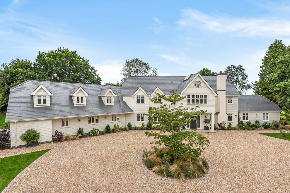 Traditional two-storey white house exterior in Hampshire with a gable roof, a shingle roof, a grey roof and clapboard siding.