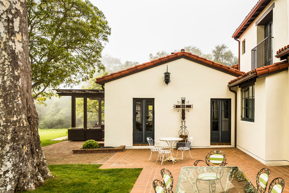Design ideas for a large mediterranean backyard verandah in Santa Barbara with brick pavers.