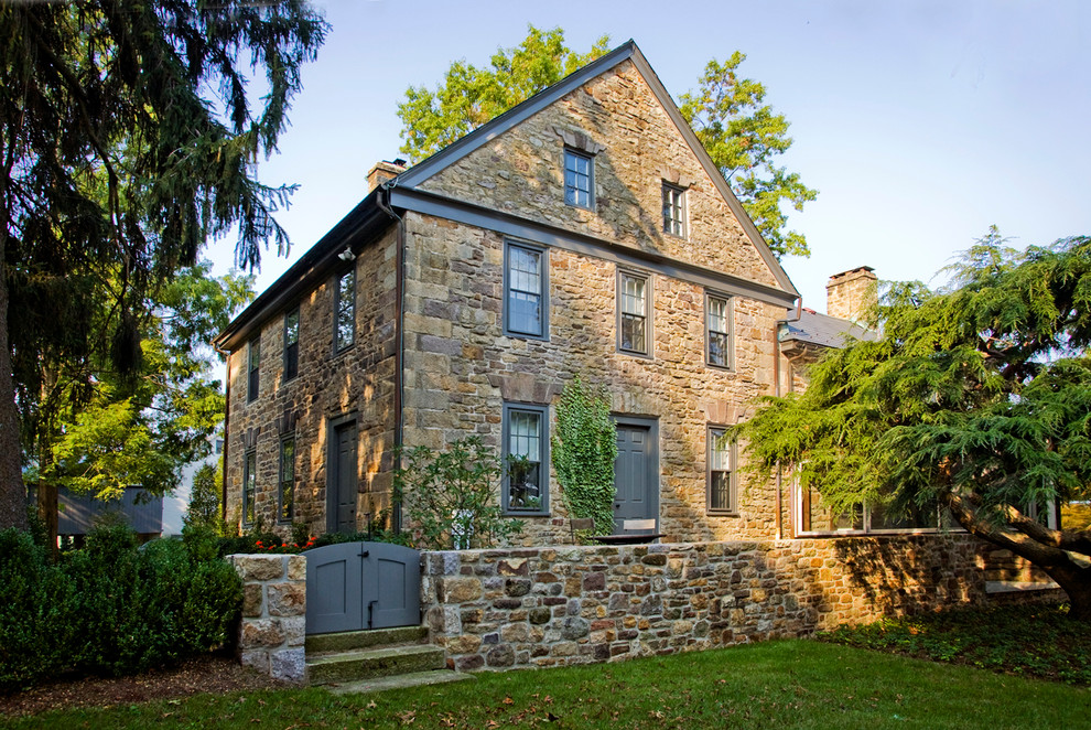 Country three-storey brown exterior in Philadelphia with stone veneer and a gable roof.