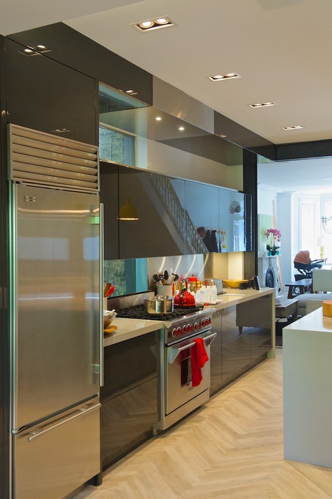 This is an example of a small modern galley separate kitchen in Toronto with an undermount sink, flat-panel cabinets, grey cabinets, quartz benchtops, grey splashback, metal splashback, stainless steel appliances, light hardwood floors and with island.